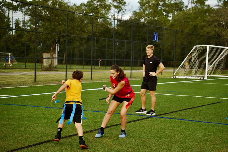 Two athletes in a flag agility drill while the coach watches